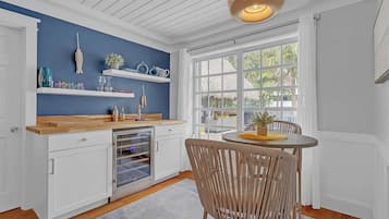 A kitchen with white cabinets, a wooden countertop, a built-in oven, and a window with a view of palm trees.