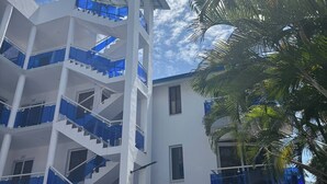 Un edificio de varios pisos con una escalera central, balcones y un cielo despejado.