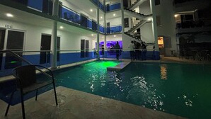 Un hotel de varios pisos con zona de piscina, balcones y una escalera.