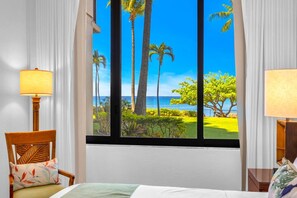 Ein Hotelzimmer mit großem Fenster und Blick auf Palmen und einen Golfplatz.