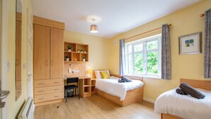 Une chambre avec deux lits, un bureau et une armoire.