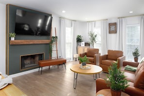 Ein modernes Wohnzimmer mit Flachbildfernseher, Kamin, Ledersofas und einem Couchtisch.