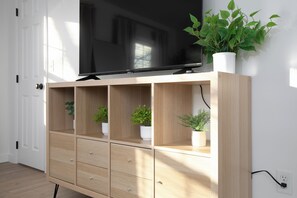 Ein Holzbüfett mit einem Flachbildfernseher, mehreren Regalen mit Topfpflanzen und einer Steckdose an der Wand.