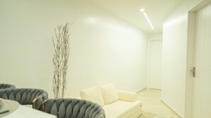 A modern living room with a sofa, a dining table, and a tall decorative plant. - Mary's Villas  (Oranjestad)