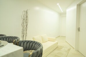 A modern living room with a sofa, a dining table, and a tall decorative plant. - Mary's Villas  (Oranjestad)