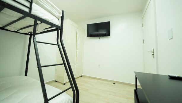 A room with bunk beds, a flat-screen TV, a door, and a desk. - Mary's Villas  (Oranjestad)