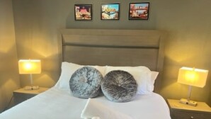 A neatly made bed with white linens, two decorative pillows, and a set of towels on the side. - Reno Spa Studio With Hot Tub and Sauna (Reno)