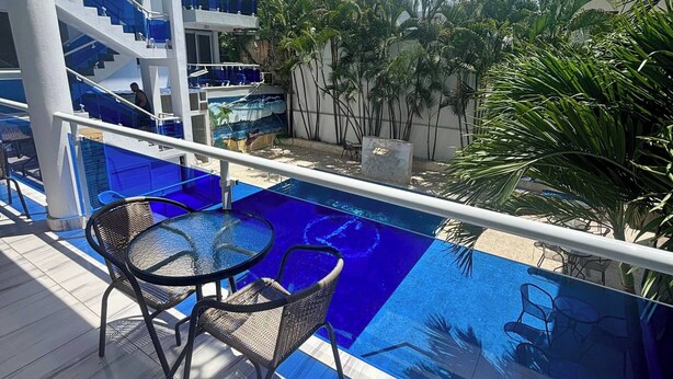Un espace piscine doté d’un plancher en verre, de coins salon extérieurs et d’un escalier menant aux niveaux supérieurs.