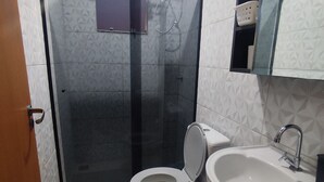 Une salle de bain avec des toilettes, un lavabo et une douche.