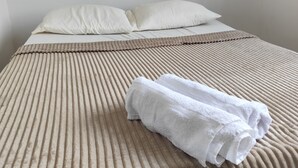 Un lit avec une couvre-lit à rayures beige et deux oreillers blancs.