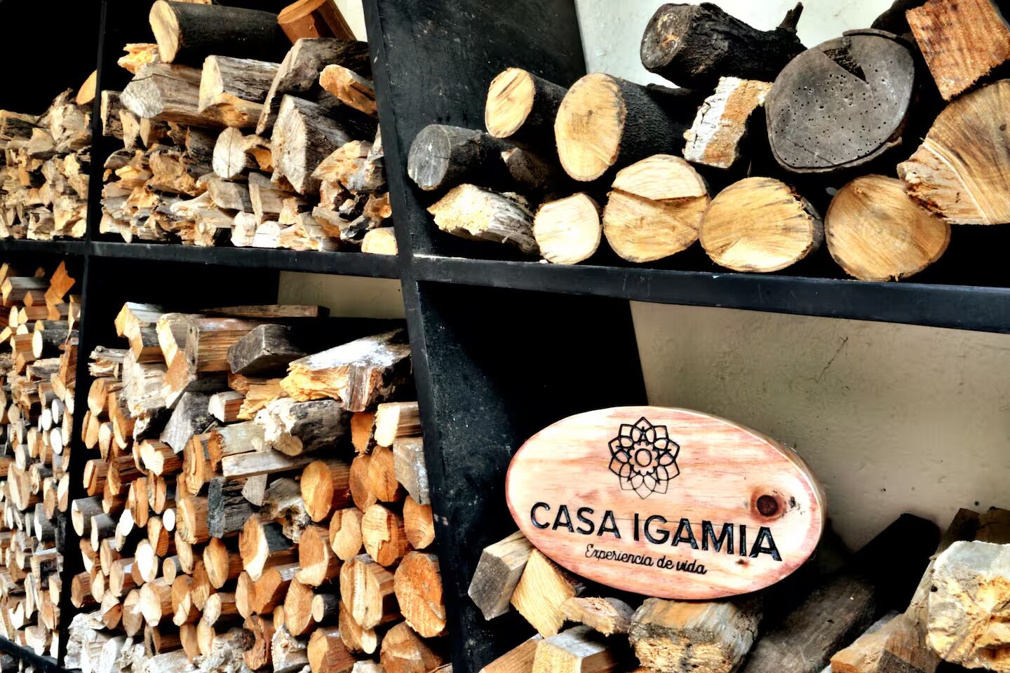Un montón de leña en un área de almacenamiento con un letrero que dice 'CASA IGAMIA'.