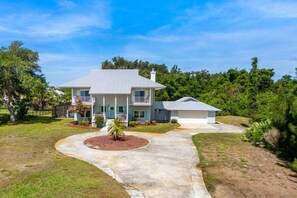 A two-story house with a covered porch, a separate garage, and a well-maintained lawn.