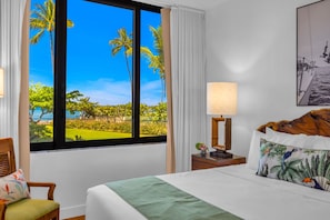 Ein Hotelzimmer mit großem Fenster, einem Bett, einem Nachttisch und einem Sessel.