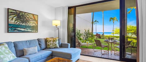 A living room with a sofa, coffee table, and a painting of a beach scene.