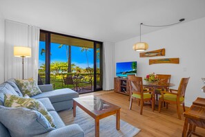 Ein Wohnzimmer mit Sofa, Couchtisch, Esstisch mit Stühlen und Fernseher.