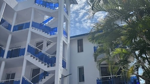 A multi-story building with a central staircase, balconies, and a clear sky. - Condo, Neuf, Balcon en Plein Coeur de Sosua 204 (Sosúa)