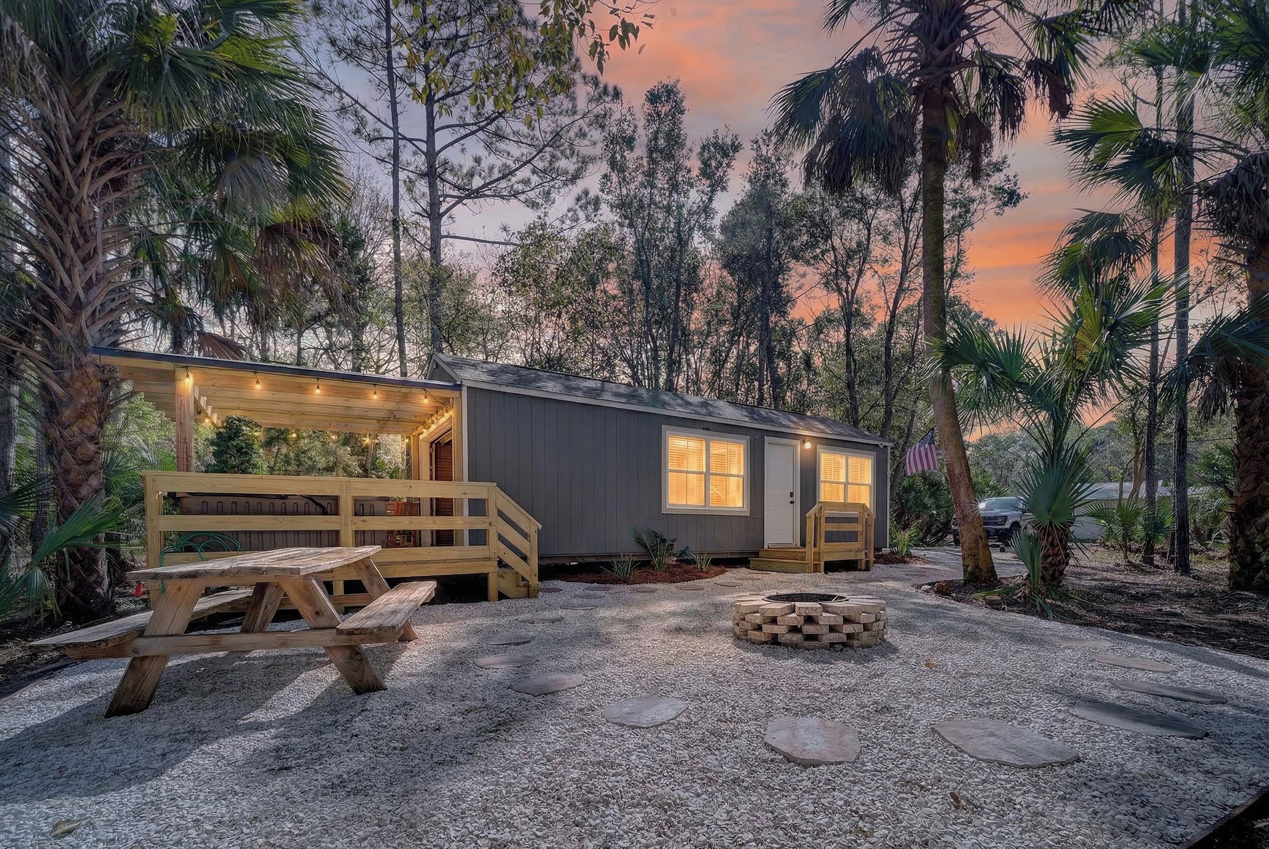 Casa Gaucho at dusk — reclaimed wood, warm light, and a fire pit waiting in the clearing.