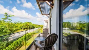 Ein Balkon mit Glasgeländer, zwei Stühlen und einem Tisch.