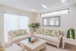 A living room with two white sofas, a coffee table, and a side table with a plant. - Modern Poolside Villa in Vistacana Near Downtown (Punta Cana)