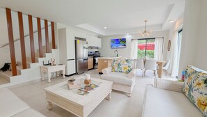 Ein modernes Wohnzimmer mit Sofa, Couchtisch und einem Essbereich mit Stühlen.