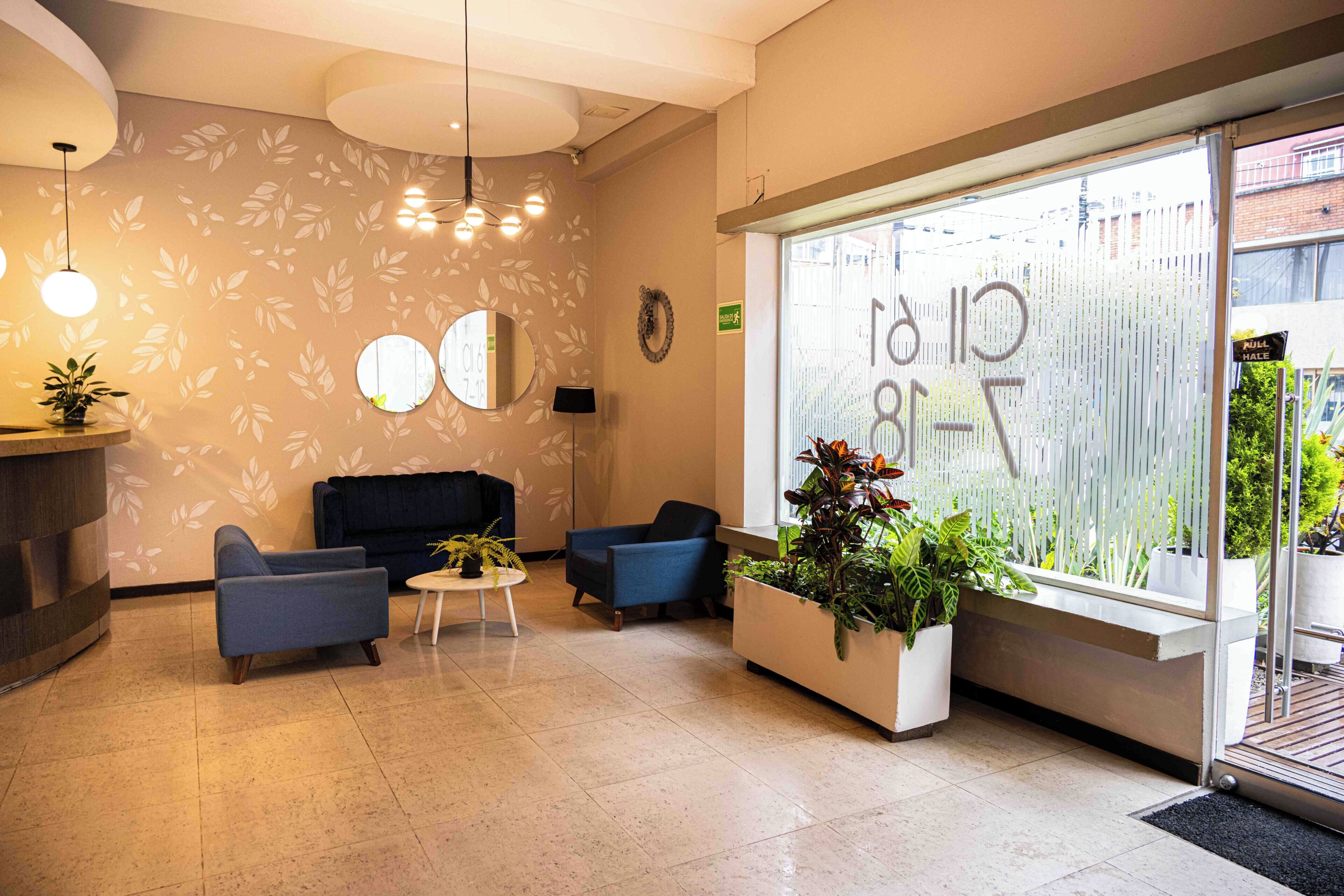 Un espace d’accueil comprenant un canapé, des fauteuils, une petite table et des plantes en pot.