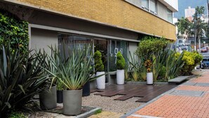 A modern building with a brick facade, large windows, and a paved entrance area with potted plants. - 617 Living  (Bogotá)