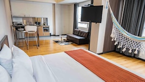 A hotel room with a bed, a sofa, a TV, a kitchen area, and a hammock. - 617 Living  (Bogotá)