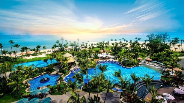 Ein Resort mit mehreren Schwimmbecken, Palmen und Blick auf den Strand.