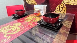 A dining table with a red and gold table runner, two red bowls, a glass jar, and a red hanging light fixture. - Asian Zen With Jacuzzi, Kitchenette, Near Victoria Sq (Sparks)