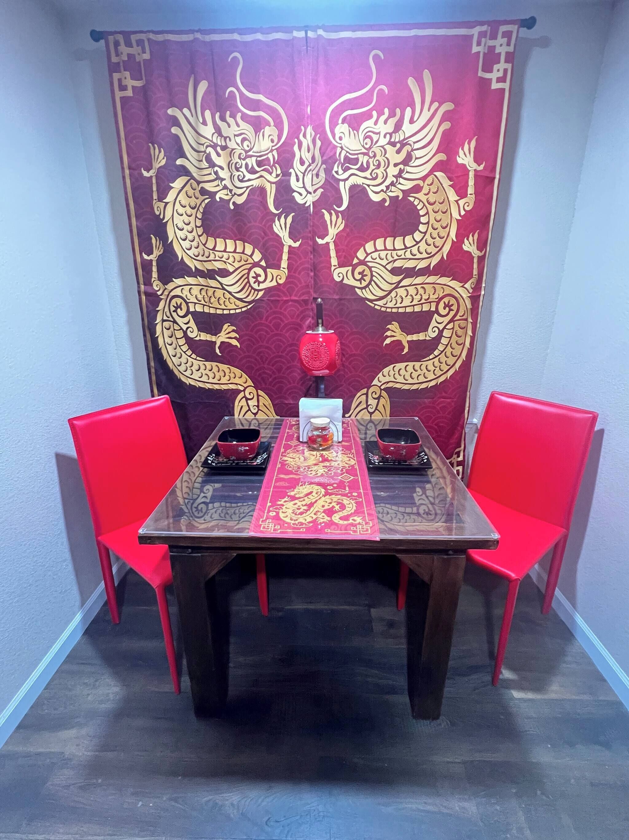 A dining table with a red table runner and two red chairs.