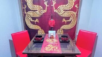 A dining table with a red table runner and two red chairs.