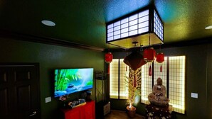 A room with a TV on a red cabinet, a statue, and a window with red lanterns. - Asian Zen With Jacuzzi, Kitchenette, Near Victoria Sq (Sparks)