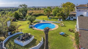 A swimming pool surrounded by a well-maintained lawn, with a view of a distant cityscape. - Ideal retreat for couples or small families (Fuseta)