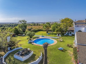 Una piscina rodeada de un césped cuidado, con vista a un horizonte urbano distante.