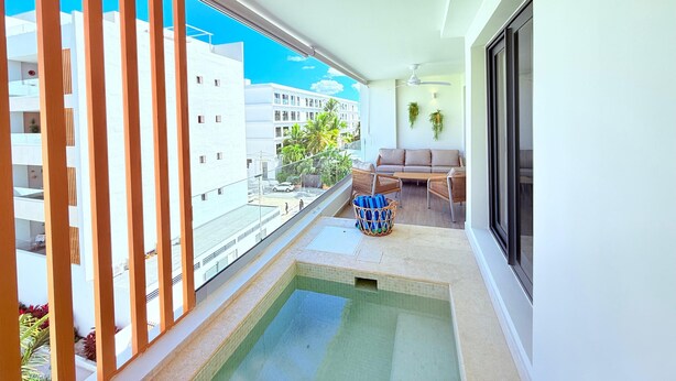 Ein Balkon mit Pool, einer Couch und einem Esstisch.