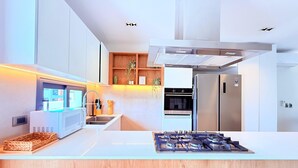 Eine moderne Küche mit Kochinsel, integrierten Geräten und einer Holz-Spritzschutzwand.
