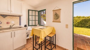 Een compacte keuken met een eethoek, een raam met uitzicht op groen en een bladdecoratie.