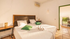 Een hotelkamer met een bed, nachtkastje, lamp en uitzicht op het groen.