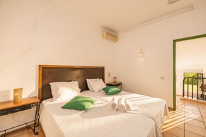 Ein Hotelzimmer mit einem Bett, einem Nachttisch, einer Lampe und Blick ins Freie.