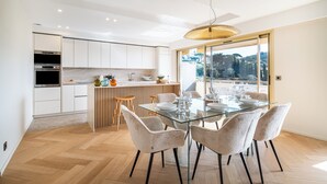 A modern kitchen with white cabinets, a built-in oven, and a wooden island. - Terrasse vue Baie de Cannes - Welkeys (Le Cannet)