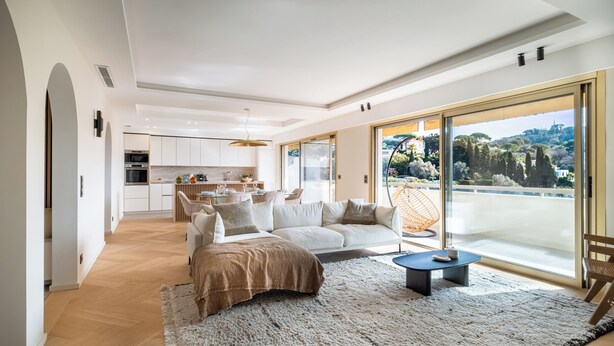 A modern living room with a large window, a sofa, a coffee table, and a view of a cityscape. - Terrasse vue Baie de Cannes - Welkeys (Le Cannet)