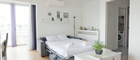 A modern bedroom with a bed, bedside table, and a view of the city.