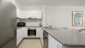 Una cocina moderna con armarios blancos, un refrigerador de acero inoxidable, un microondas, un horno y un lavaplatos.