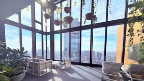 A spacious room with large windows, a seating area with sofas and chairs, and a view of the cityscape. - Modern 1-bedroom apartment with gym and pool access, centrally located near cafes, restaurants, and public transport—perfect for a comfortable city stay. (Southbank)