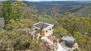 A modern house with a solar panel roof, surrounded by dense forest and hills. - Sunset Retreat in Mount Victoria (Mount Victoria)