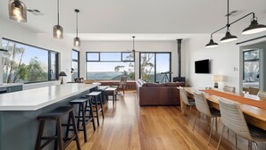 A modern kitchen with a central island, bar stools, and large windows offering views of the outdoors. - Sunset Retreat in Mount Victoria (Mount Victoria)