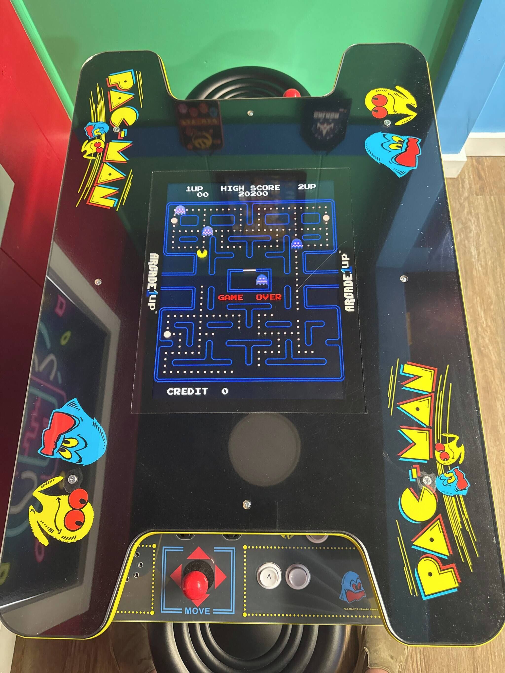 A Pac-Man arcade machine with a maze game, score display, and control buttons.