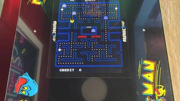 A Pac-Man arcade machine with a maze game, score display, and control buttons.