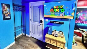 Una stanza con pareti blu, una porta, una decorazione a tema Super Mario e uno scaffale con diversi oggetti.