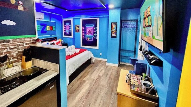 Una stanza con un letto, una scrivania, una TV e un angolo cottura.